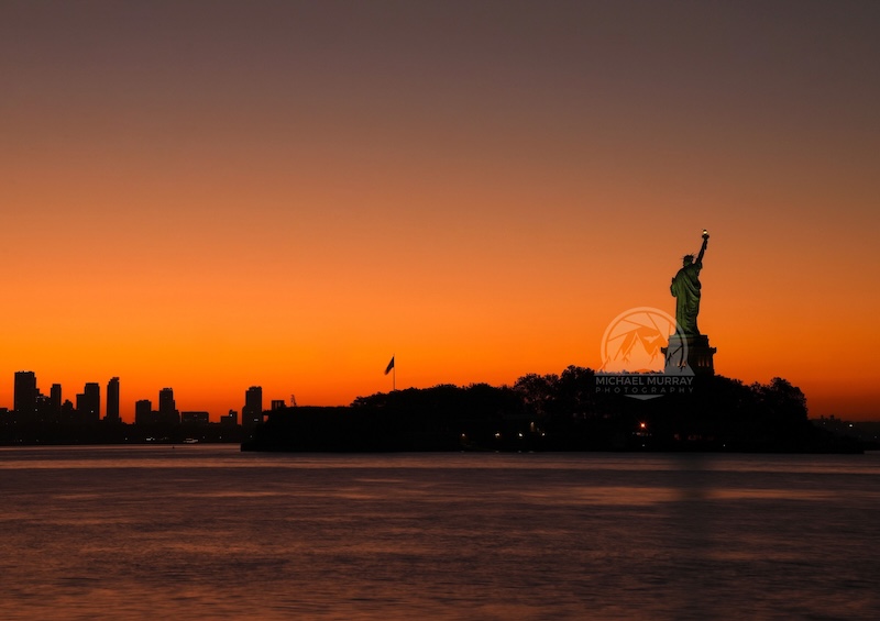 Sunrise view photo of the Statue of Liberty famous landmark, picture seen from Liberty State Park in Jersey City.