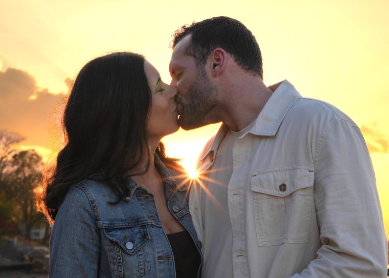 Couple kissing as the sun shines between them during a Lake Erie Ohio engagement photo session.