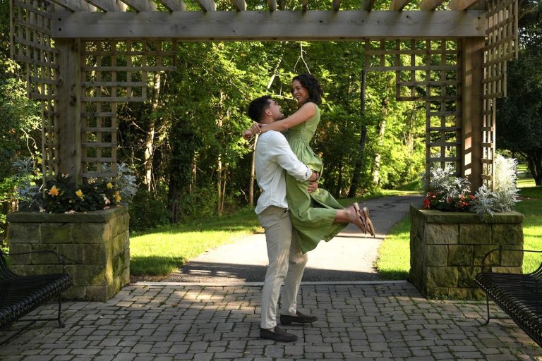 Couple smiles during a lift beneath the garden arbor at Schoepfle Garden in Lorain County, Ohio.