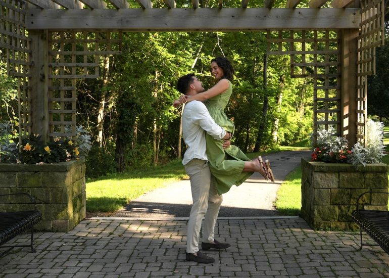 Couple smiles during a lift beneath the garden arbor at Schoepfle Garden in Lorain County, Ohio.