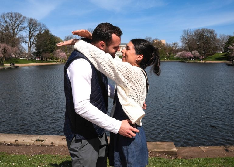 Engaged couple smiling beside the water and spring blossoms at Wade Lagoon in University Circle Cleveland.