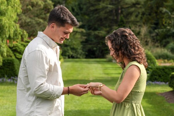 Couple looking at a ring together on the lawn at Schoepfle Garden during an Ohio engagement photo session.